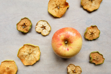 Fresh apple with pieces of dry apples on the table, top view