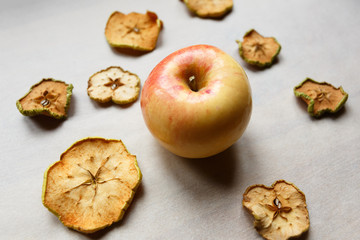 Fresh apple with pieces of dry apples on the table, top view