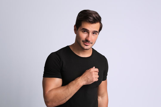 Portrait of handsome young man in black t-shirt on grey background