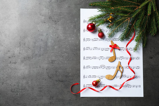 Christmas decorations, notes and music sheet on grey stone table, flat lay with space for text