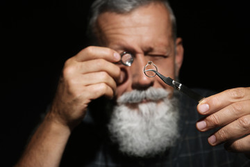 Male jeweler evaluating diamond ring in workshop, closeup view