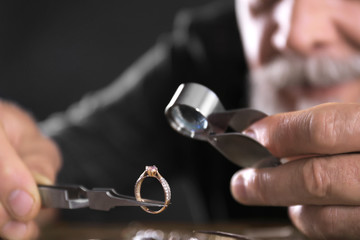Male jeweler evaluating diamond ring in workshop, closeup view