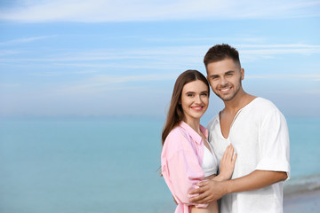 Young woman in bikini with her boyfriend on beach, space for text. Lovely couple