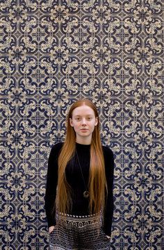 young woman in front of tile wall