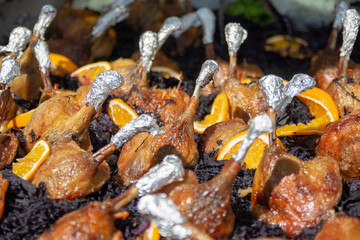 Roast chicken thighs in a paella dish on a street food festival.