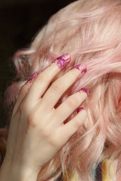 Woman hand with glitter covered fingers touching blond hair