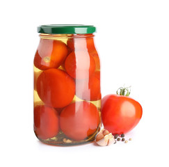 Pickled tomatoes in glass jar and products on white background