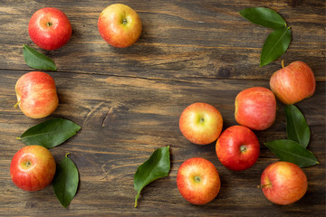 Red and pink apples with  green leaves on wooden table , close up from above , copy space
