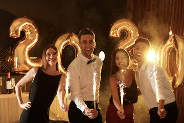 Young people celebrating New Year in club. Golden 2020 balloons on background