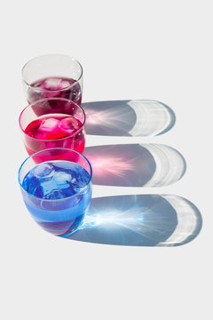 Row of glasses with colorful drinks with ice cubes