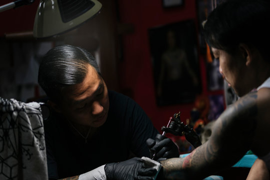 Professional asian tattooer makes a tattoo.