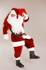 Authentic Santa Claus with bag full of gifts on grey background