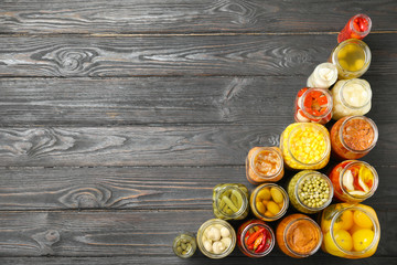 Jars of pickled vegetables on black wooden table, flat lay. Space for text