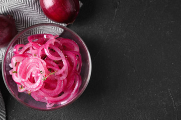 Bowl with tasty pickled onions on black table, top view. Space for text