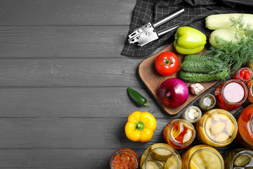 Flat lay composition with jars of pickled vegetables on grey wooden table. Space for text