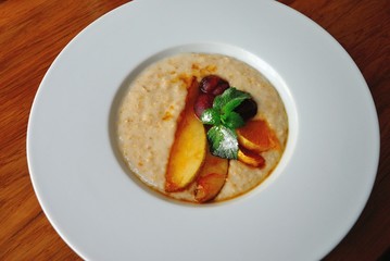 Oatmeal porridge served with fruits and mint leaves