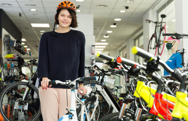  girl  buyer in helmet standing with sport bicycle