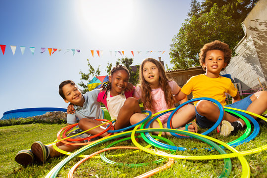Group of diverse kids sit with hula color rings