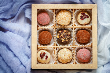 Assorted truffle set  of dark and white chocolate with almonds, hazelnuts and dried cranberries or cherries in a paper box. Candy.  Sweet gift. Holiday concept. Copy space, Selective focus