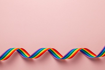 LGBT rainbow ribbon pride tape symbol. Pink background. Copy space for text.