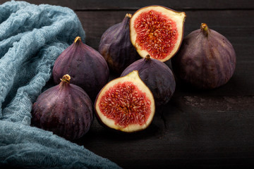 Fresh figs lie on a black wooden table. Beautiful blue fig fruits close up