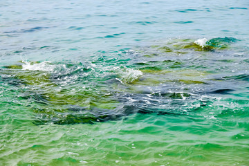 Dangerous underwater rock on beach at high tide. Costa Brava, Spain.