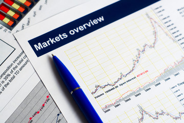 Markets overview report with a pen