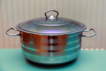 Metal pan . A stainless steel pot on a green background .