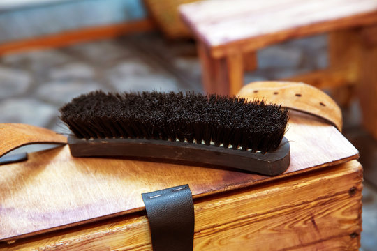 Shoe brush on wooden table. Footwear care item . Large black Horse Hair Shoe Brush and polishing shoes on a wooden table .