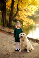 happy pretty girl 3-4 years old with a white dog in the fall in the park, beautiful sunset, evening