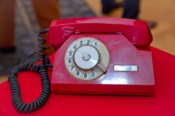 Contact us concept .Still life with retro red phone on wooden red table over grunge background .Red antique vintage analog telephone dialing or scrolling phone on red table.