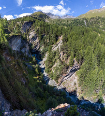 Schlucht im Hochgebirge mit tosendem Bergbach und Blick auf Berggipfel