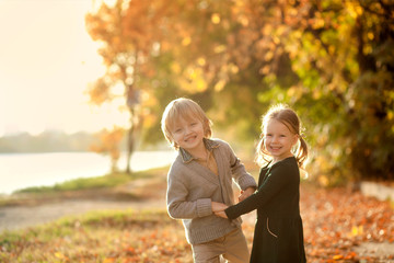 happy cute children a boy of 4-5 years and a girl of 3-4 years on nature in the park in autumn, beautiful nature, attention and care of brother and sister, friends