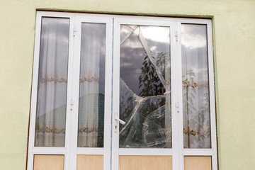 A broken glass window in an aluminum frame door. Door is padlocked