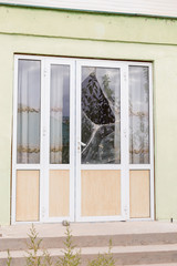 A broken glass window in an aluminum frame door. Door is padlocked
