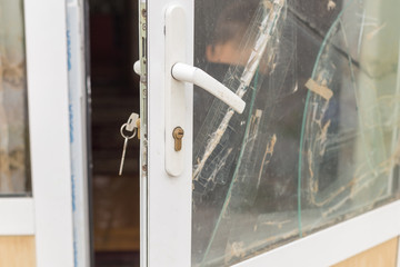 A broken glass window in an aluminum frame door. Door is padlocked