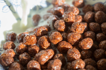 Chocolate cereal balls in milk as food background