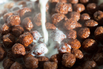 Chocolate cereal balls in milk as food background