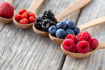 Ripe berries in wooden spoons