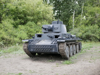 Fototapeta premium German medium tank of the Second World war in working order. the tank is painted black against a background of green trees in summer .