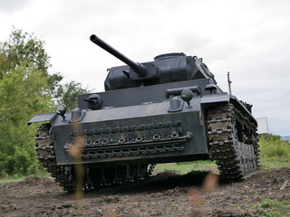 Fototapeta premium German medium tank of the Second World war in working order. the tank is painted black against a background of green trees in summer .