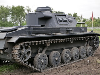 Fototapeta na wymiar German medium tank of the Second World war in working order. the tank is painted black against a background of green trees in summer .