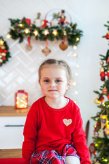Portrait of a girl sitting in the kitchen decorated for Christmas