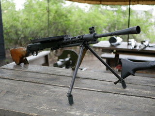 Samples of Soviet automatic weapons of the second world war. Machine guns and machine guns on a wooden table outside on a summer day.