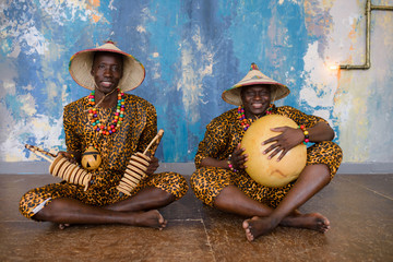 African artist in traditional clothes playing on ethnic musical instruments