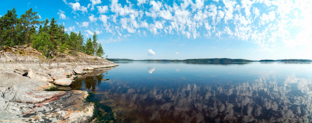 Rocky shore of the island on lake Ladoga with the reflection of clouds . Ladoga Skerries, Karelia