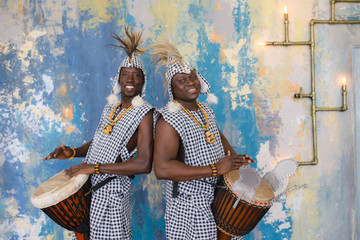 A group of people in traditional african costumes playing jembe drums
