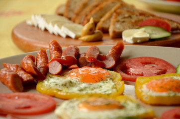 Fototapeta na wymiar breakfast fried eggs with vegetables and sausages and croutons 