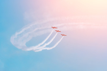 Group of three turboprop aircraft flying in the sky leaving a white smoky trail.