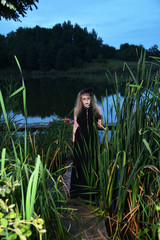Girl with gothic makeup on the background of the swamp. Mystical style shooting. Fashion photo session of a beautiful young woman in a natural location.